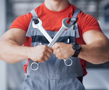 Garagiste qui tiens des outils en forme de croix