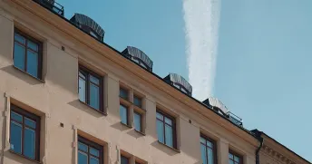 Beige, äldre lägenhetshus i Stockholm, Sverige med blå himmel i bakgrunden.