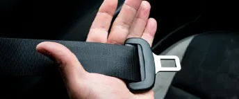 Närbild på en hand som håller i ett bilbälte