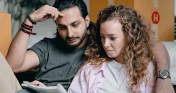 dolda-fel-försäkring Ung kvinna och man omgivna av flyttlådor tittar i ett skrivblock.