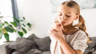 ersättning ärr.jpg Blond flicka blåser på ett sår på armbågen.