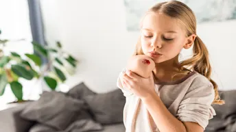 ersättning ärr.jpg Blond flicka blåser på ett sår på armbågen.