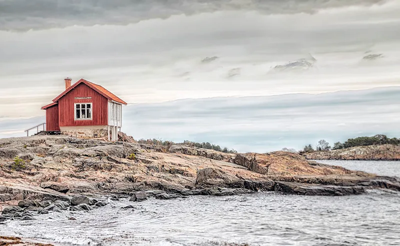 äldre stuga Röd stuga intill havet.