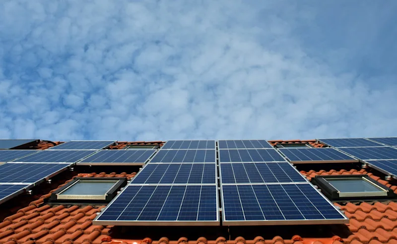 Solceller på hustak Solceller på tegelhustak med blå himmel i bakgrunden