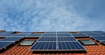 Solceller på hustak Solceller på tegelhustak med blå himmel i bakgrunden