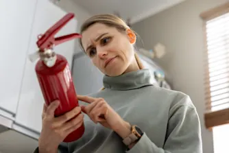 Brandförsäkring: Så skyddar du dig mot brand i hemmet Kvinna läser instruktioner på brandsläckare