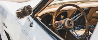 hur man startar en bil.webp En vit, klassisk bil med bruna och beiga detaljer och ratt.