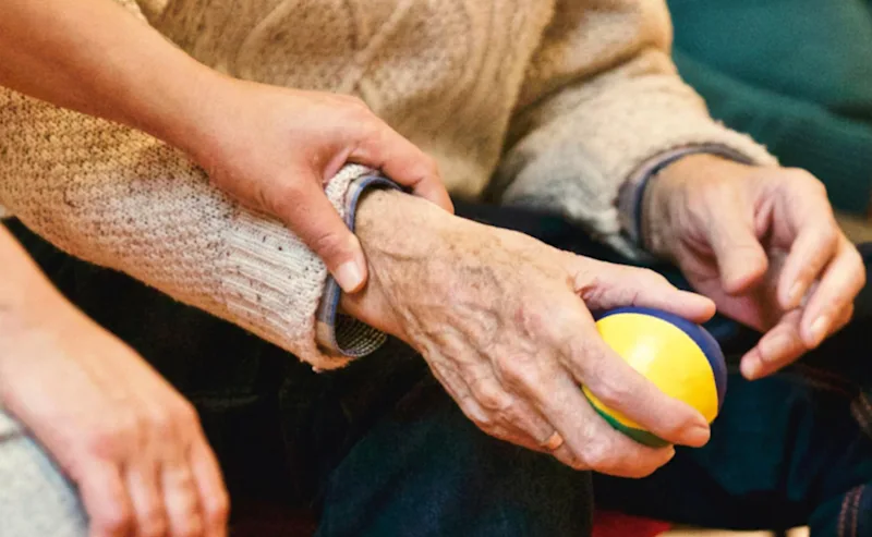 anhorigbehorighet En åldrad hand håller i en jongleringsboll. Någon annan håller i personens handled.