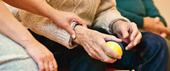 anhorigbehorighet En åldrad hand håller i en jongleringsboll. Någon annan håller i personens handled.