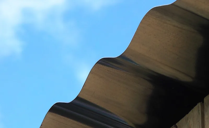 plattak-solceller.jpeg Kanten av ett grått plåttak med blå himmel i bakgrunden.