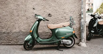 Moped Trafikförsäkring Grön vespa parkerad längs en stenvägg