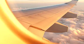 Flygplansfönster Utsikten från ett flygplansfönster med vit flygplansvinge och moln i bakgrunden
