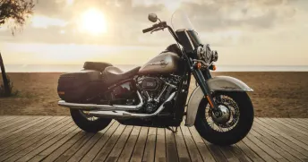 Harley Davidson motorcykel vid strand i motljus. 