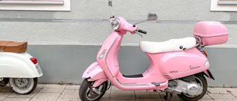 Vilken moped ska man köpa? Rosa vespa parkerad längs en husvägg.