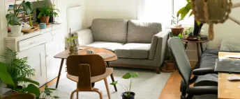 Vardagsrum med vita väggar, grå soffa, skrivbordsstol och soffbordet Lövet från IKEA.