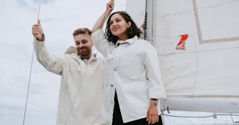 sälja båt Man och kvinna som ler står på segelbåt och blickar ut.