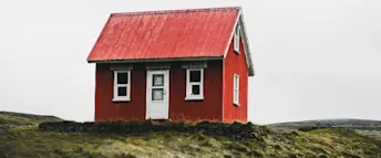 rimligt att ha i lån.png Litet rött hus stående på en gräskulle