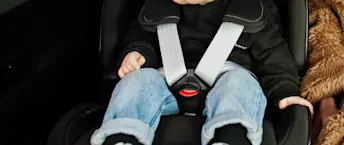 ISOFIX Barn sitter fastspänd i en bilbarnsstol.