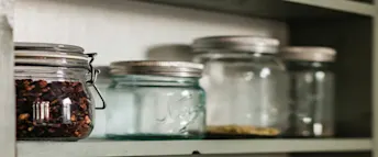 Köksförvaring med glasburkar på hylla Glasburkar med olika innehåll står prydligt uppradade på en hylla i köket.