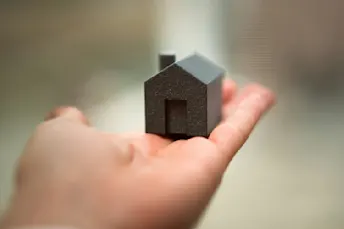 lagfart.jpg Ett litet svart hus som hålls ut i en hand.