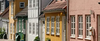 Färgglada radhus i charmig stadsmiljö – trygghet viktigt vid uthyrning Fasad av pittoreska och färgglada radhus i rad med vita fönster, perfekta som exempel på bostäder som kan hyras ut i en trygg och försäkrad miljö.