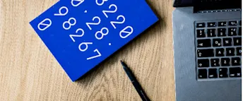 ta-ut-lon-enskild-firma.jpg Närbild på ett block med siffror bredvid en laptop