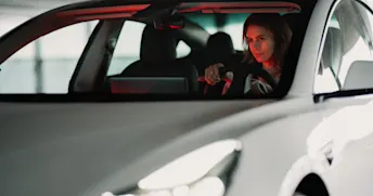 företagsbil Kvinna sitter i en vit bil i ett garage.