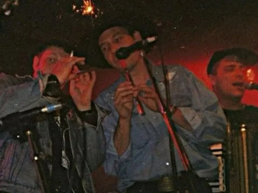Three men, including Dav Powell, stand together with musical instruments, ready to perform.