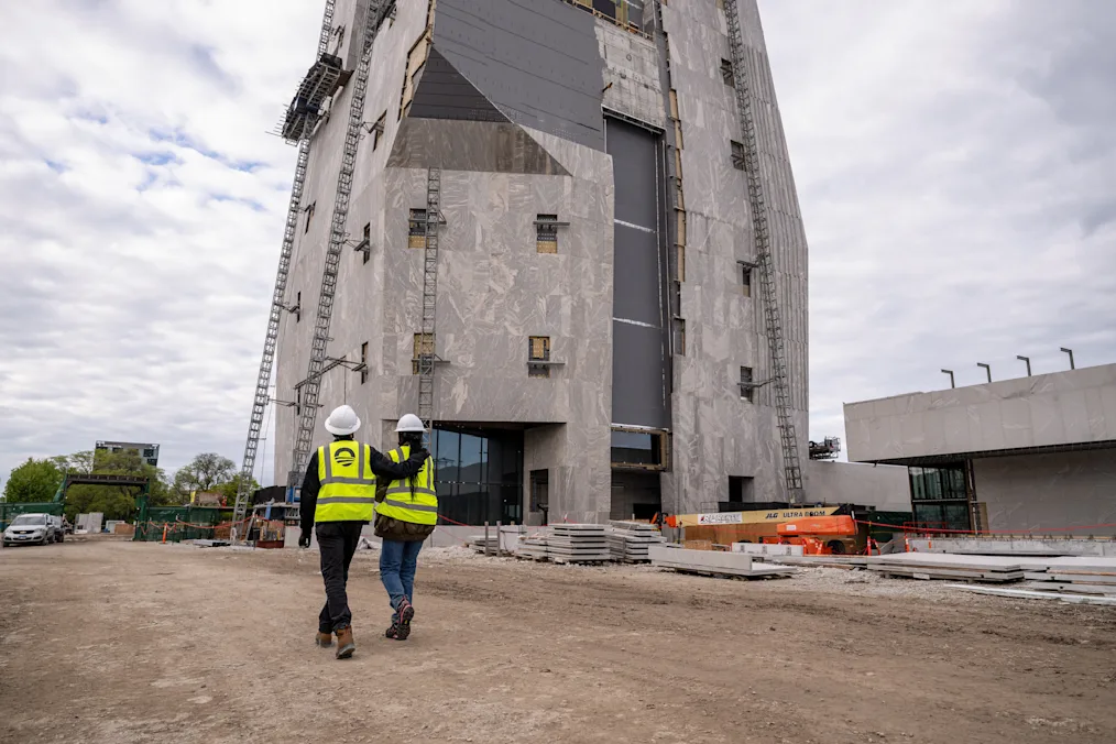 President and Mrs. Obama stand side by side in hard hats and yellow vests at the site of the Obama Presidential Center.