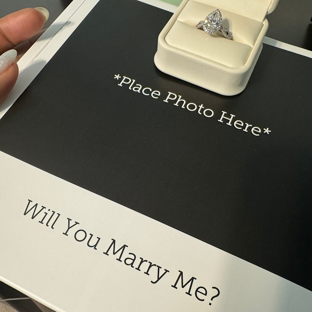 A close up of Vanessa’s pear shaped engagement ring atop of the custom book.