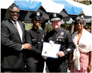 Captain II Shannon White, a Black woman with a medium skin tone, smiles for a photo with her father Captain Paul Enox, mother, and Jim McDonnell, chief of police for the Los Angeles Police Department.