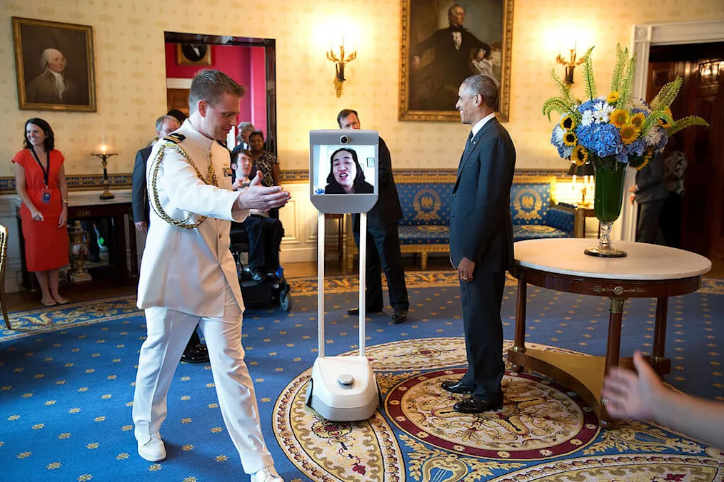 One social aide helps push the next guest towards the President and another helps pull them out of the room.