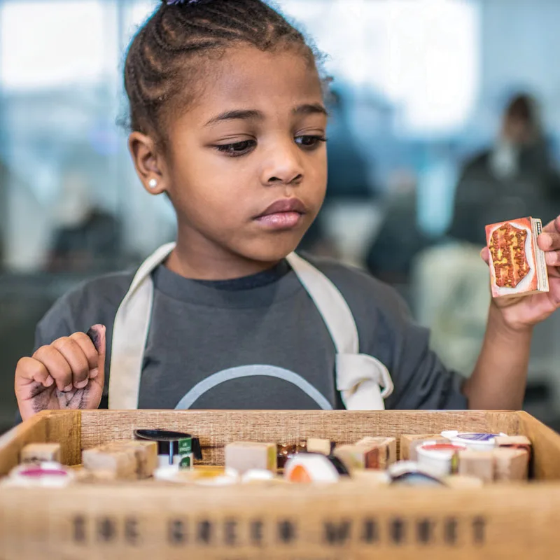 A young girl studies a box of items during the Obama Foundation's MLK Day of Service volunteer event. 