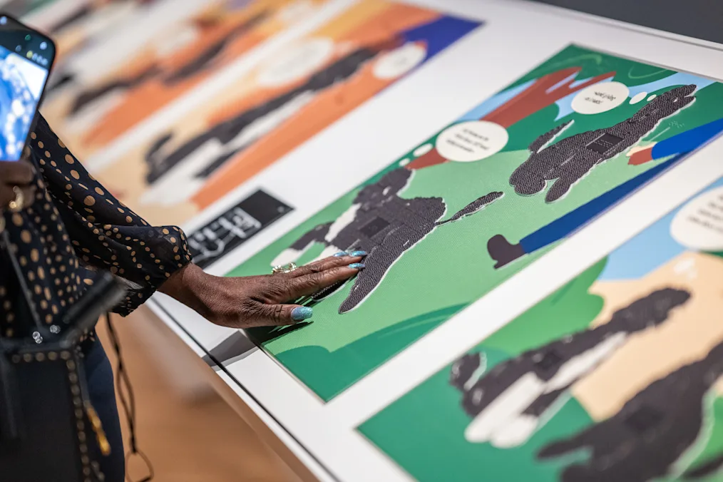 Attendees view an exhibit about Bo and Sunny’s life at the White House in Chicago, IL. There is a hand touching the screen. The screen features cartoon drawings of Obama family dogs Bo and Sunny.