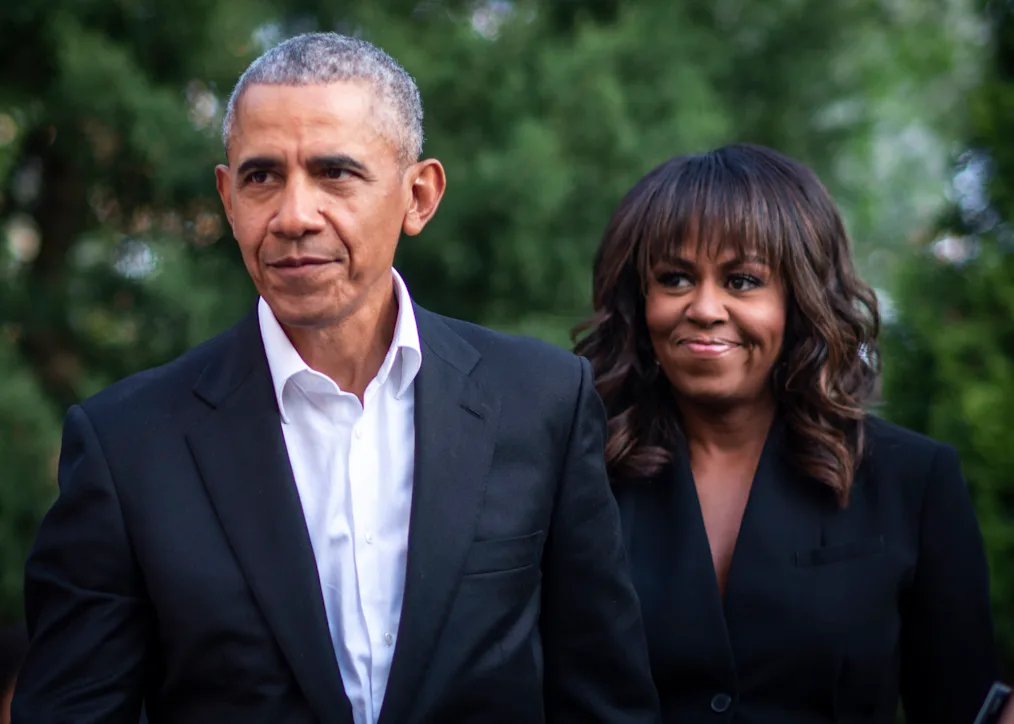 President Obama poses for a photo with Michelle Obama. They are standing outdoors.