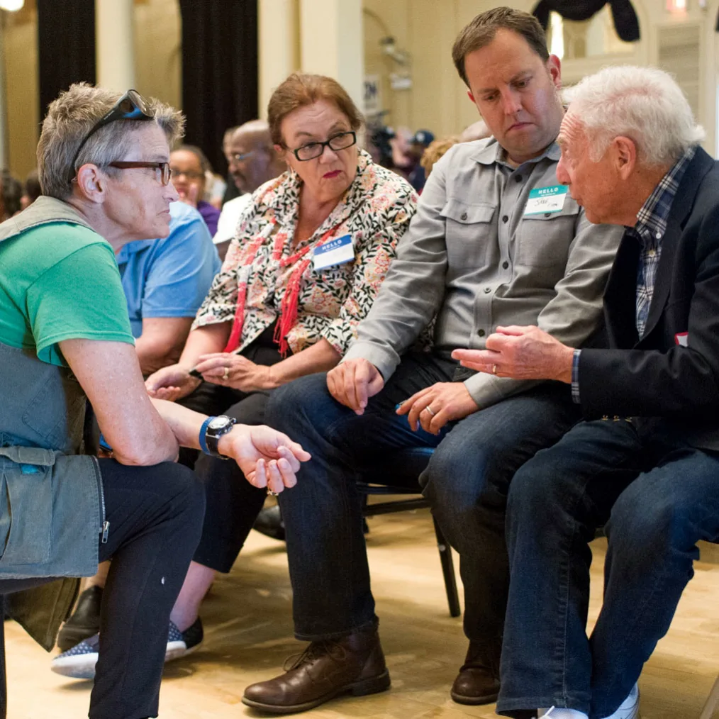 A group of older people converse at a meeting.