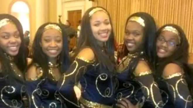 A group of baton twirlers smile to camera for a group photo.