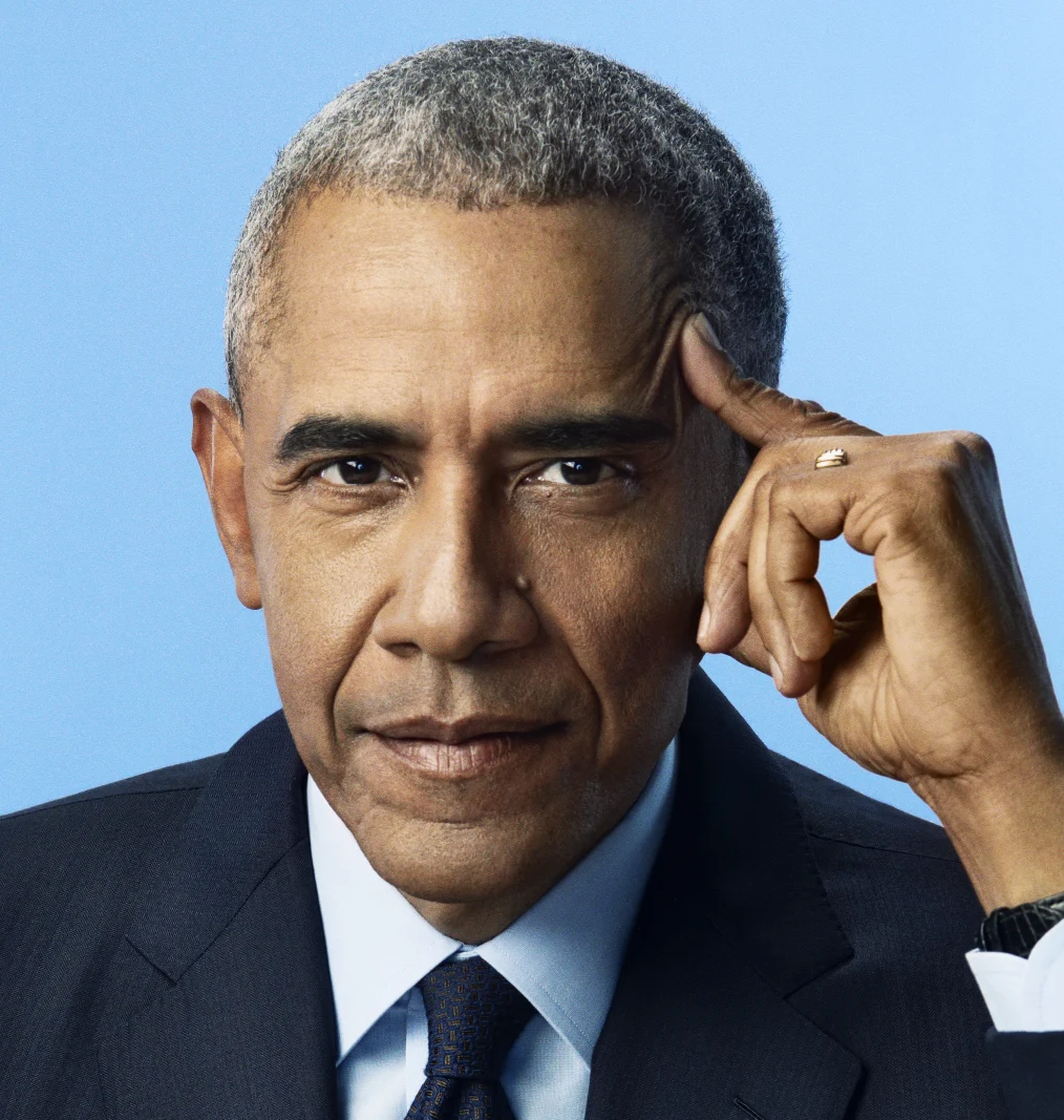 A headshot of President Obama looking directly at the camera, with his hand raised to the side of his head and one finger touching his temple. He has a serious expression on his face. He wears a suite and tie.