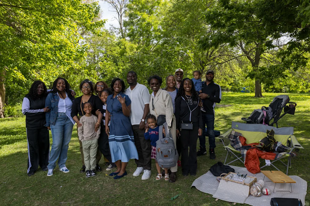 A group photo of Purvis and Vanessa’s family after the proposal with their family. All are Black people with a range of light to dark skin tone. All are smiling.