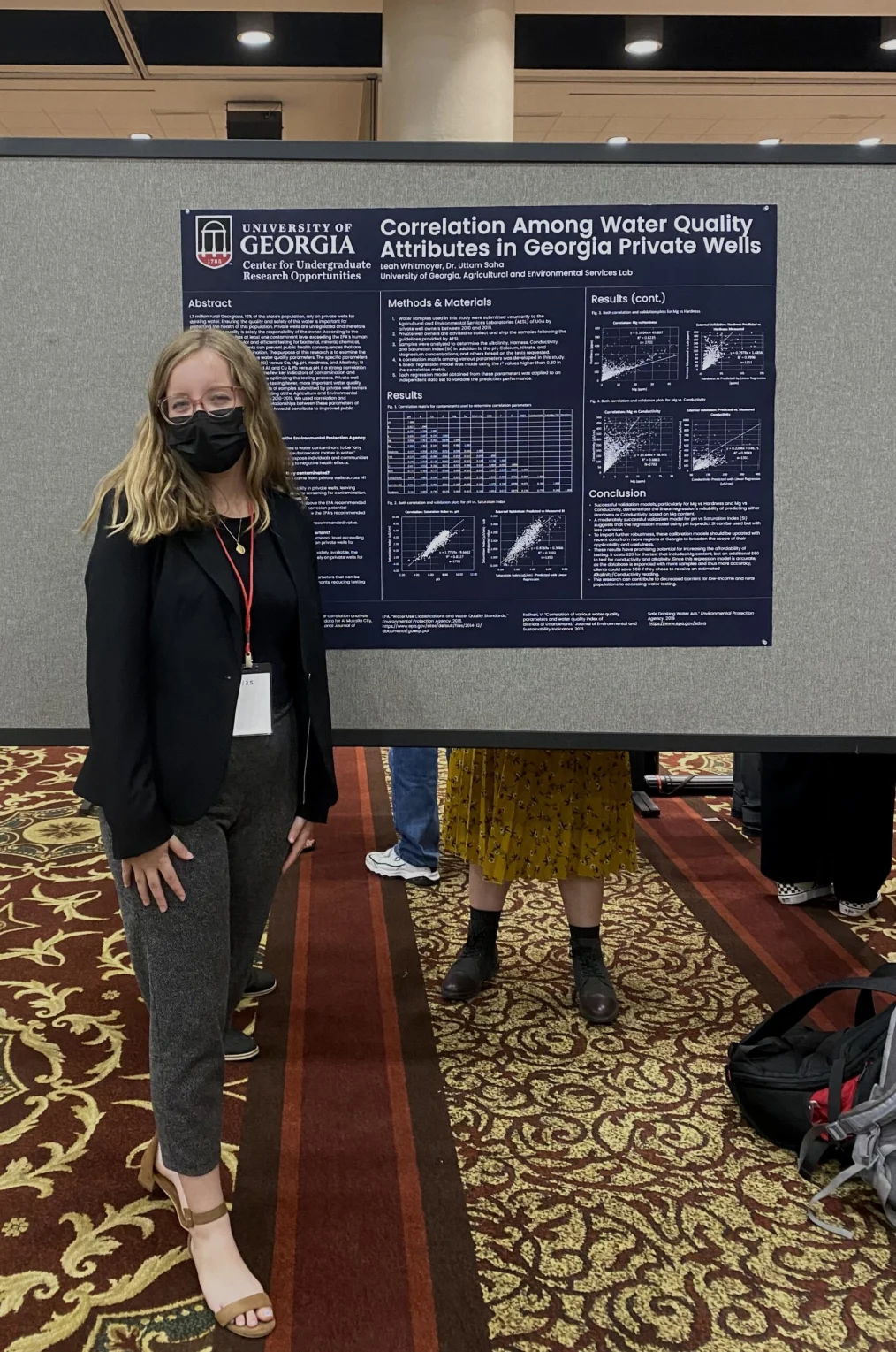 Leah Whitmoyer presents water quality research at the University of Georgia undergraduate research symposium. She is wearing glasses and a face mask as she stands in front of a poster that reads, “Correlation among water quality attributes in Georgia private wells.”