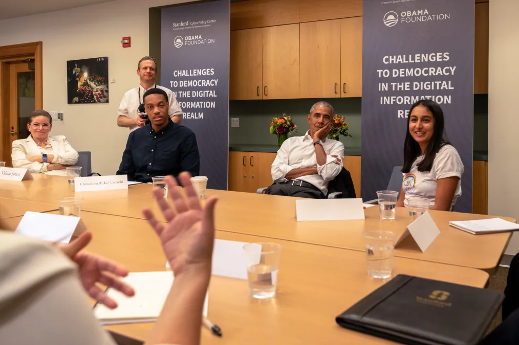 President Obama sitting at a table with other people in a meeting 