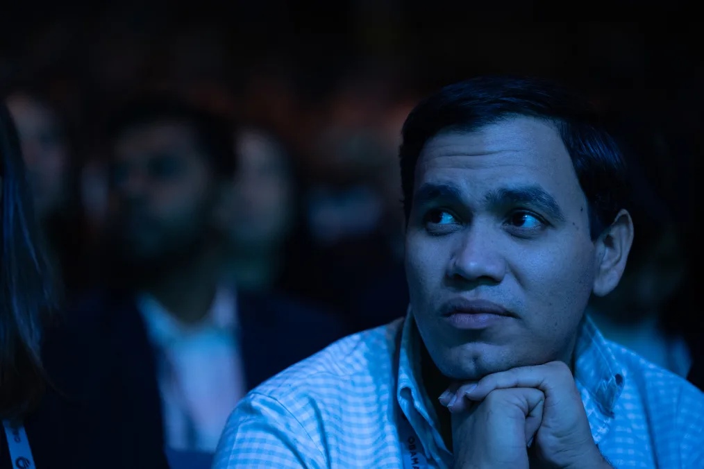 uan Carlos Monterrey, a man with black hair and a medium skin tone, looks on attentively as he listens to speakers at the Obama Foundation Democracy Forum. 
