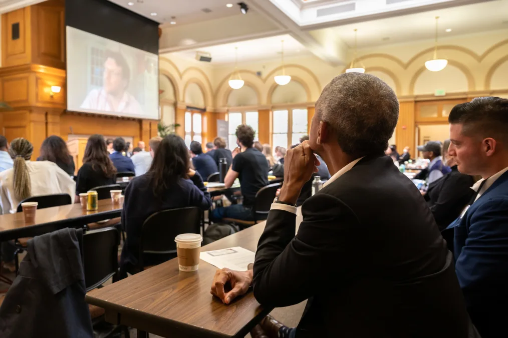 President Obama and other people of various skin tones sit and watch what was being shown on the  projector
