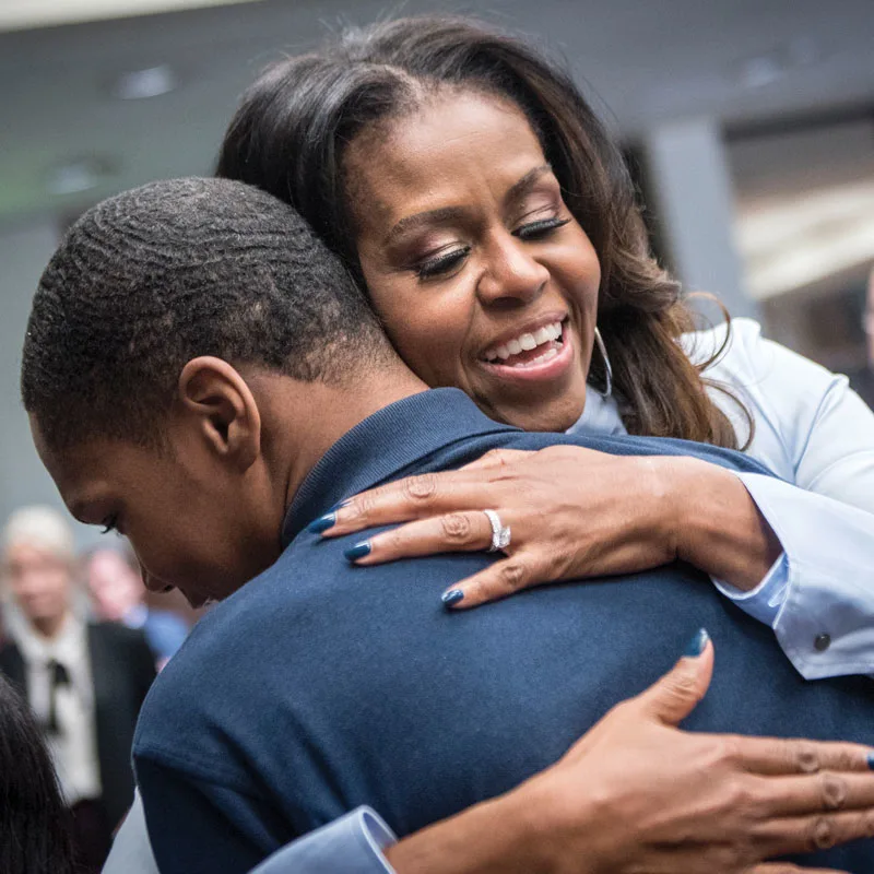 Mrs. Obama hugs a young male student.