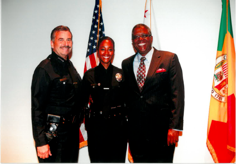 Capt. Shannon White, a Black woman with a medium skin tone, stands next to her father Capt. Paul Enox and Jim McDonnell, chief of police for the Los Angeles Police Department.