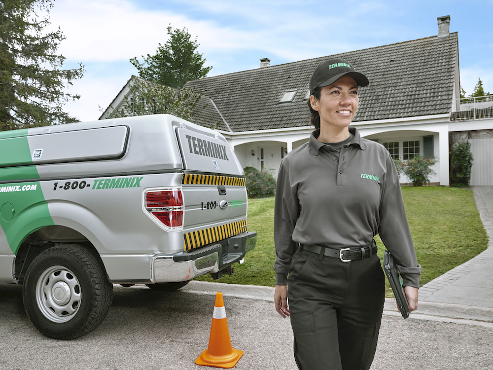A Terminix technician smiles in front of a house. 