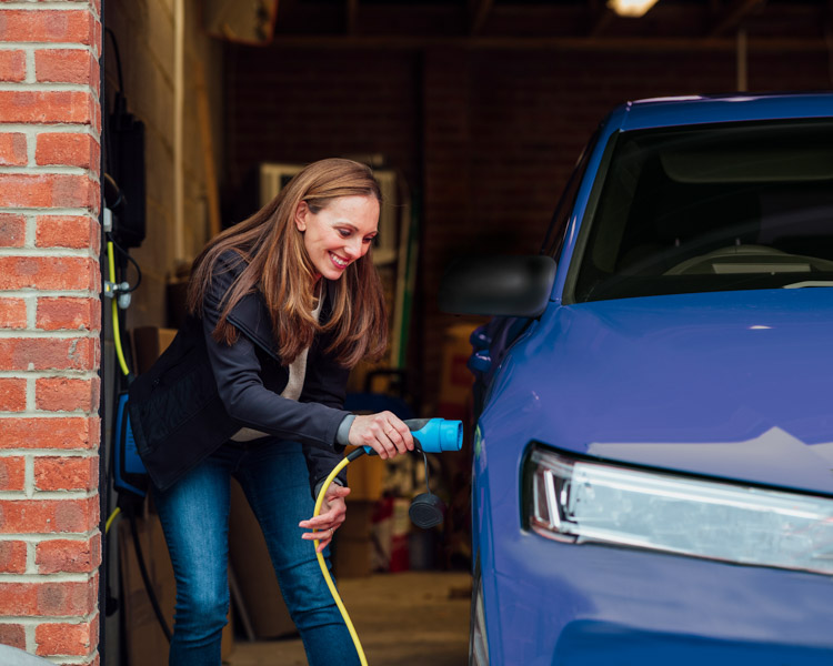 A woman plugging in an EV charging cable to her car