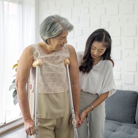 Young Asian woman help her grandma walk by using axilla crutches