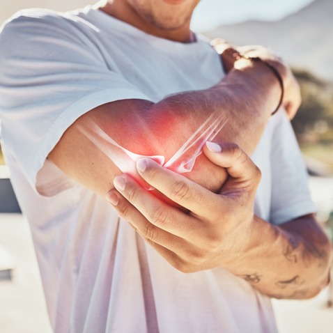 Man Managing Elbow Joint Pain Outdoors