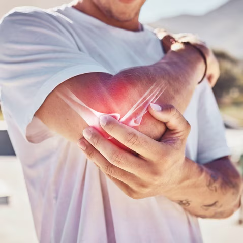 Man Managing Elbow Joint Pain Outdoors
